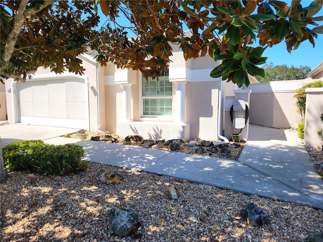 view of front of house featuring fence, a garage, driveway, and stucco siding