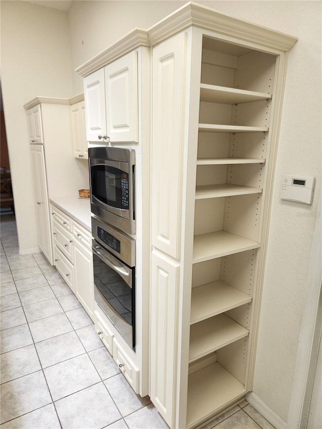 kitchen featuring stainless steel appliances, light tile patterned flooring, white cabinets, light countertops, and baseboards