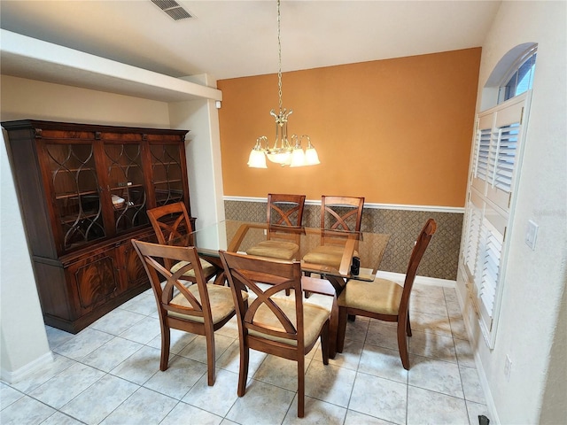 dining area featuring a notable chandelier, visible vents, light tile patterned flooring, and a wainscoted wall