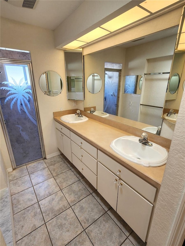 bathroom featuring tile patterned flooring, double vanity, a stall shower, and a sink