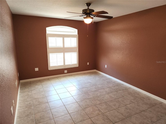 unfurnished room with baseboards, light tile patterned flooring, a ceiling fan, and a textured wall