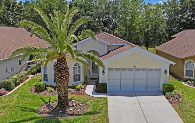 mediterranean / spanish home featuring a garage and a front lawn