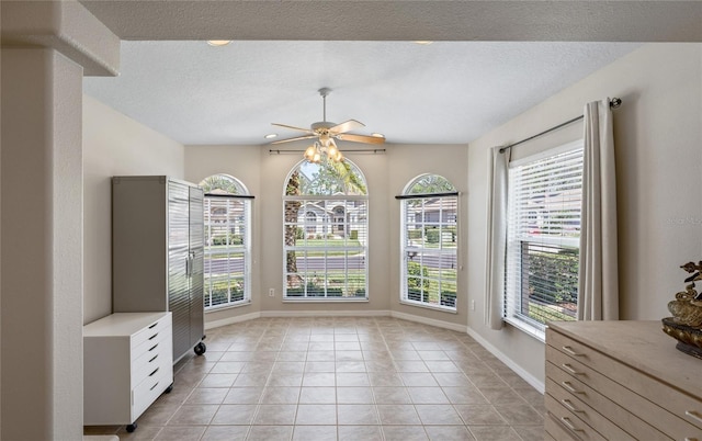 unfurnished dining area featuring light tile patterned flooring, ceiling fan, and a textured ceiling