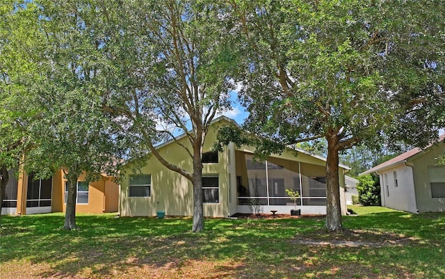 back of house with a sunroom and a lawn