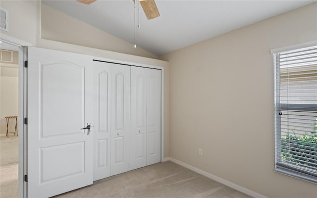 unfurnished bedroom featuring ceiling fan, a closet, lofted ceiling, and light carpet