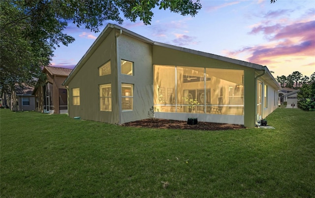 property exterior at dusk featuring a lawn