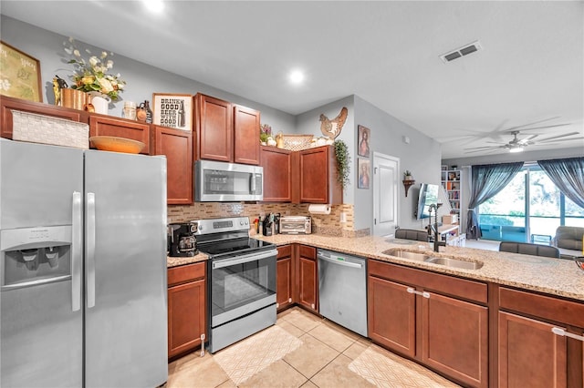 kitchen with light tile patterned flooring, sink, appliances with stainless steel finishes, light stone countertops, and decorative backsplash