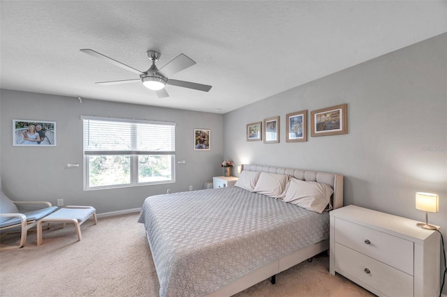 bedroom featuring light carpet, a textured ceiling, and ceiling fan