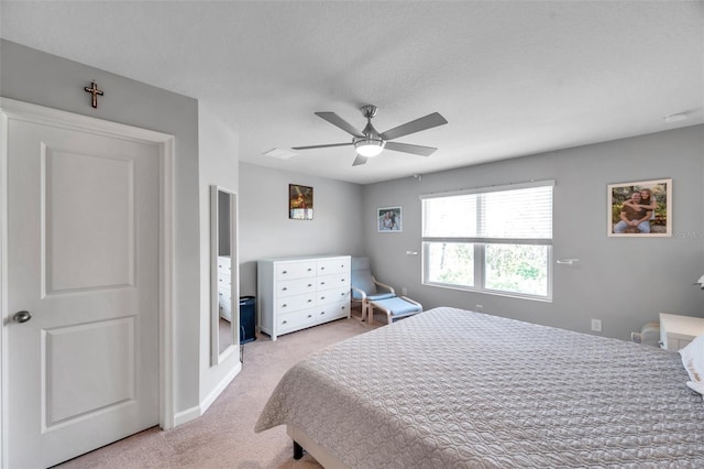 bedroom featuring light carpet, a textured ceiling, and ceiling fan