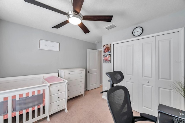 bedroom with ceiling fan, light carpet, and a closet