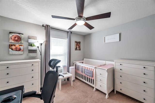 bedroom featuring light carpet, ceiling fan, and a textured ceiling