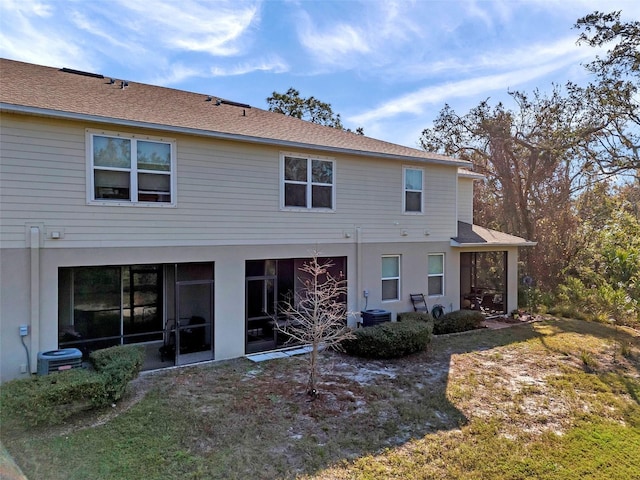 rear view of property featuring cooling unit and a lawn