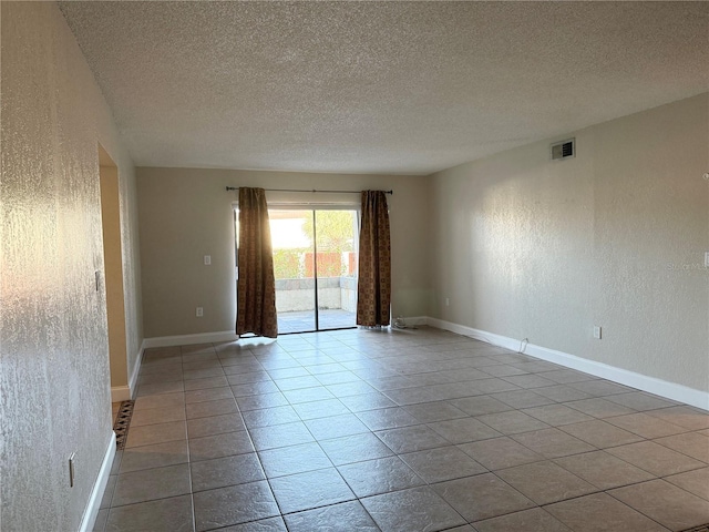 tiled empty room with a textured ceiling