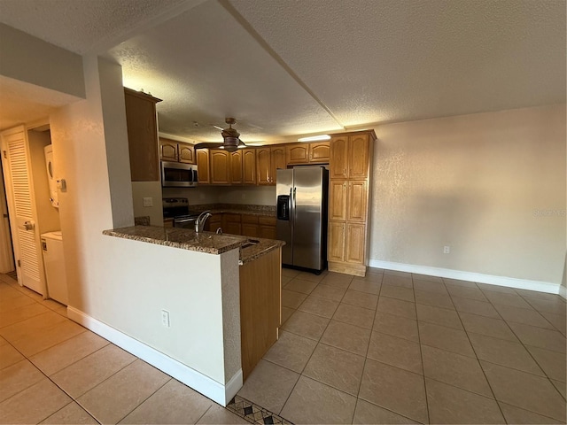 kitchen featuring light tile patterned floors, stainless steel appliances, kitchen peninsula, and a textured ceiling