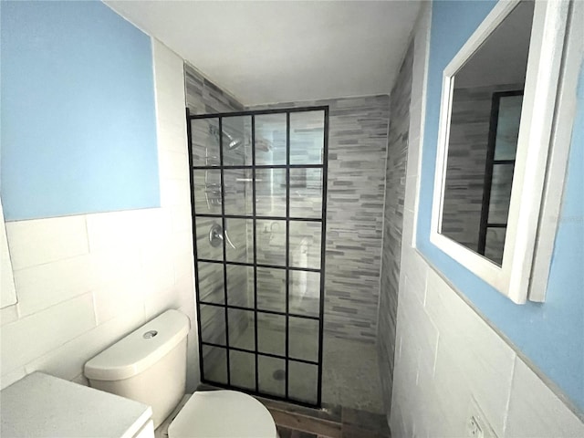 bathroom with tile walls, toilet, and tiled shower