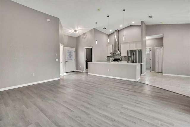 unfurnished living room with light hardwood / wood-style floors and high vaulted ceiling