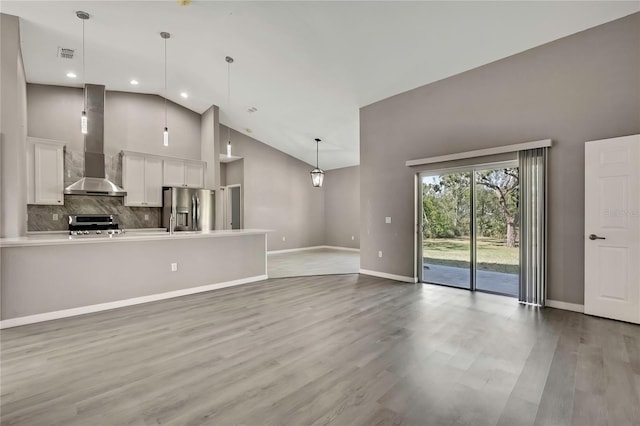 unfurnished living room with high vaulted ceiling and light hardwood / wood-style floors