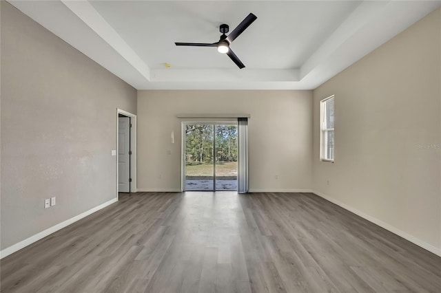 unfurnished room with ceiling fan, a raised ceiling, and light wood-type flooring