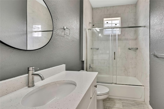 full bathroom with hardwood / wood-style flooring, enclosed tub / shower combo, vanity, and toilet