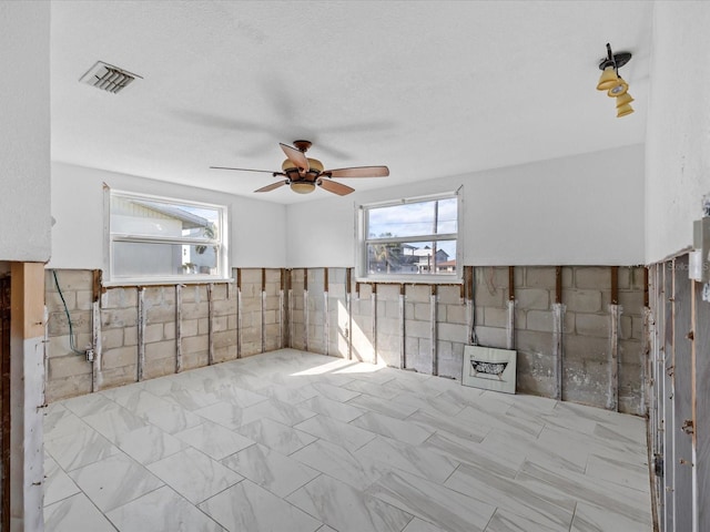 empty room with ceiling fan and tile walls