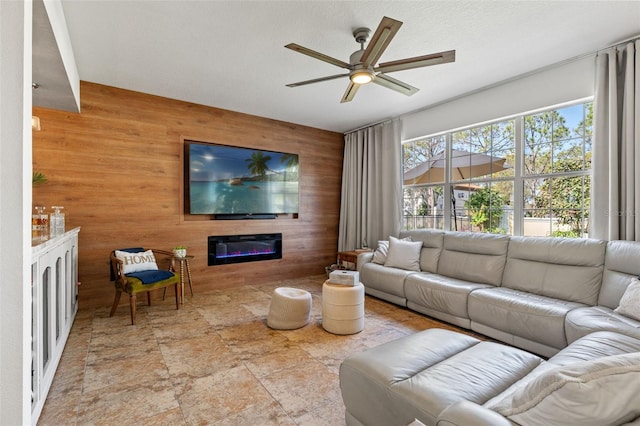 living room with a textured ceiling, ceiling fan, and wood walls