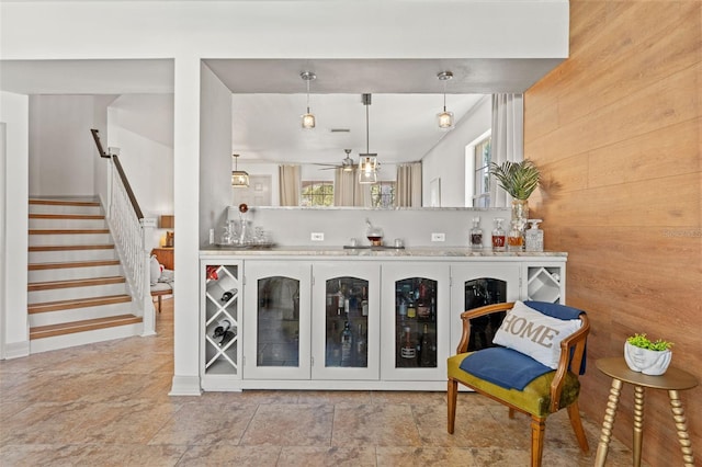 interior space with pendant lighting, wooden walls, and ceiling fan