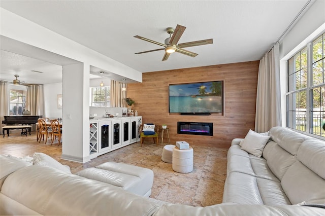 living room with ceiling fan, wooden walls, and a textured ceiling