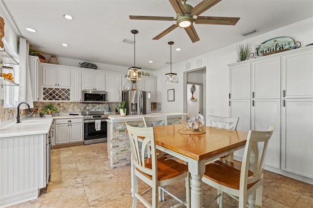 kitchen featuring pendant lighting, sink, appliances with stainless steel finishes, white cabinetry, and decorative backsplash