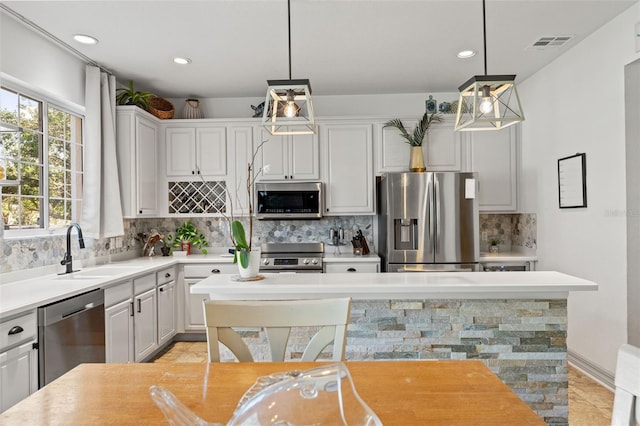 kitchen featuring appliances with stainless steel finishes, sink, decorative backsplash, and decorative light fixtures