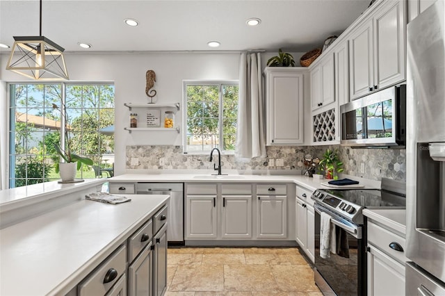 kitchen with pendant lighting, white cabinetry, sink, decorative backsplash, and stainless steel appliances