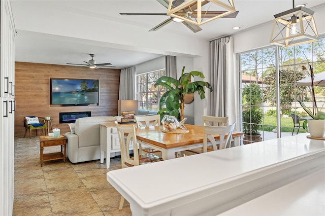 dining space with ceiling fan and wood walls