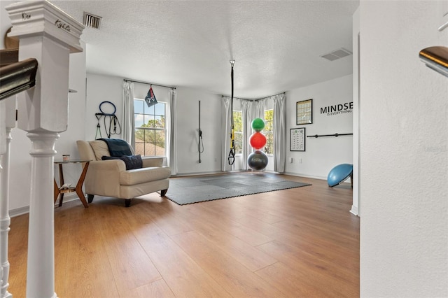 exercise room featuring wood-type flooring and a textured ceiling