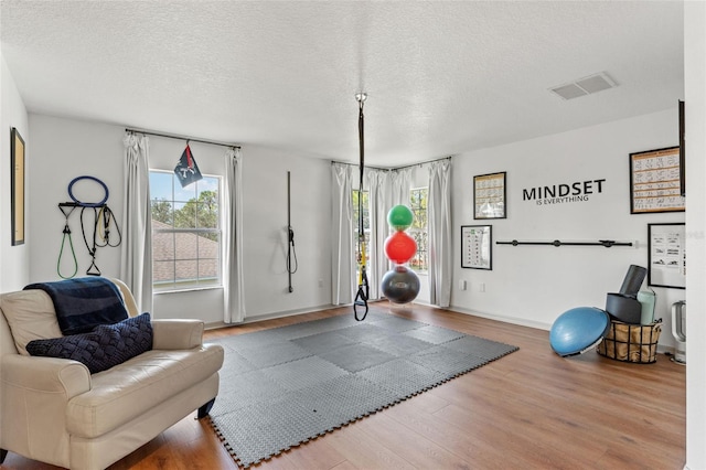 workout area featuring wood-type flooring and a textured ceiling