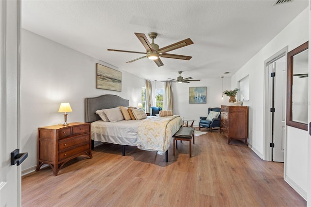 bedroom featuring ceiling fan, a textured ceiling, and light wood-type flooring