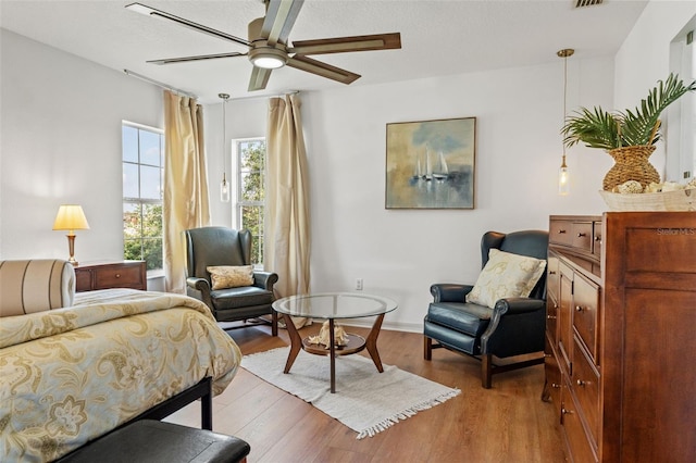 bedroom with ceiling fan, light hardwood / wood-style floors, and a textured ceiling