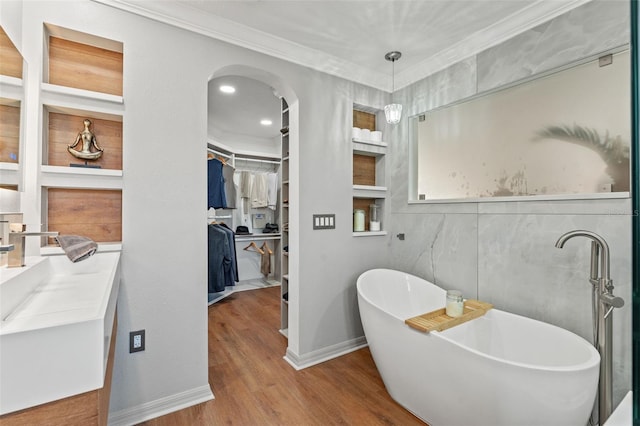 bathroom featuring built in features, hardwood / wood-style flooring, vanity, a washtub, and crown molding