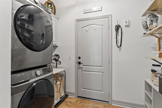 laundry area with cabinets and stacked washer / drying machine