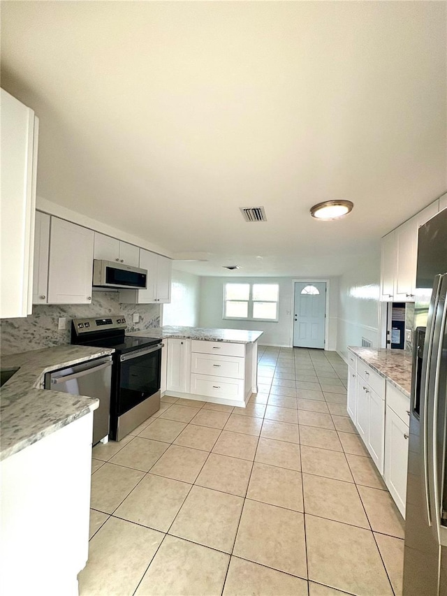 kitchen featuring white cabinetry, light tile patterned floors, kitchen peninsula, and appliances with stainless steel finishes