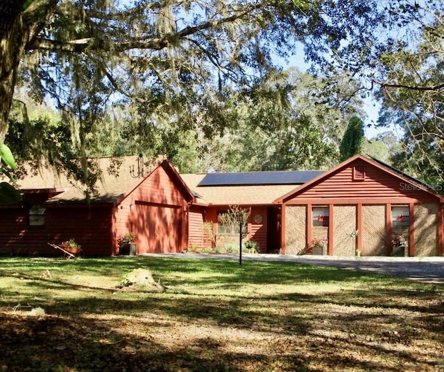 view of front of property with roof mounted solar panels and a front lawn