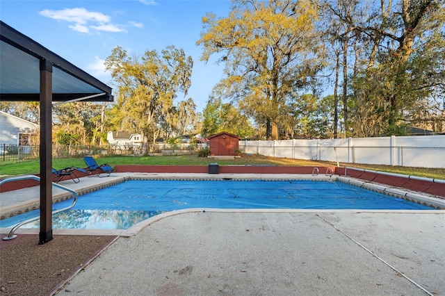 view of pool featuring a storage shed, a fenced backyard, and an outbuilding