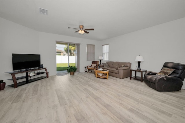 living room featuring light wood-type flooring, visible vents, and ceiling fan