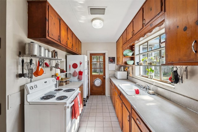 kitchen featuring brown cabinets, light countertops, white appliances, and visible vents