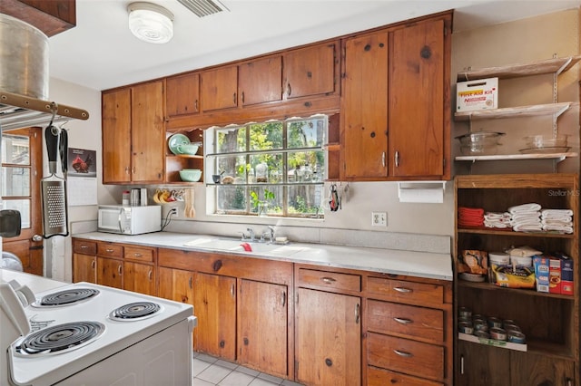 kitchen with white appliances, open shelves, light countertops, and brown cabinetry