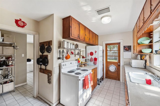 kitchen featuring white appliances, a sink, visible vents, light countertops, and brown cabinets