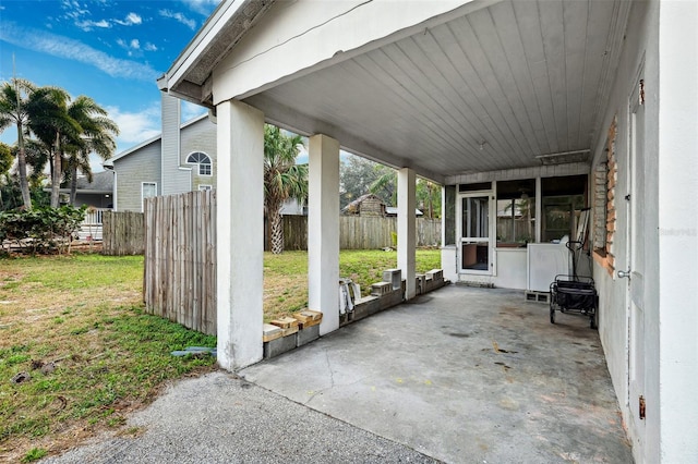 view of patio / terrace featuring fence and a sunroom