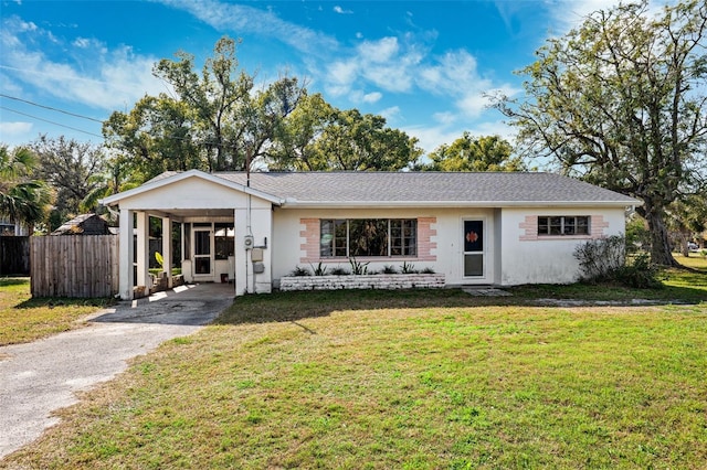 ranch-style house with driveway, an attached carport, fence, a front lawn, and stucco siding