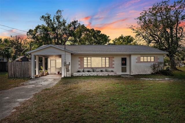 view of front of house featuring an attached carport, a lawn, driveway, and fence