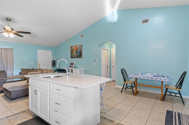 kitchen with sink, a center island with sink, light tile patterned floors, ceiling fan, and white cabinets