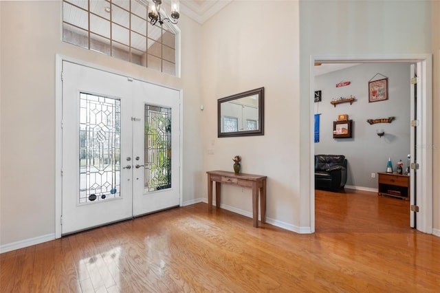 entrance foyer featuring french doors, crown molding, hardwood / wood-style floors, and a high ceiling