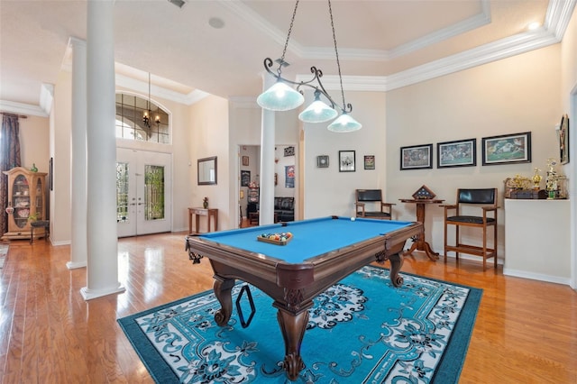 game room with hardwood / wood-style floors, decorative columns, a tray ceiling, ornamental molding, and french doors